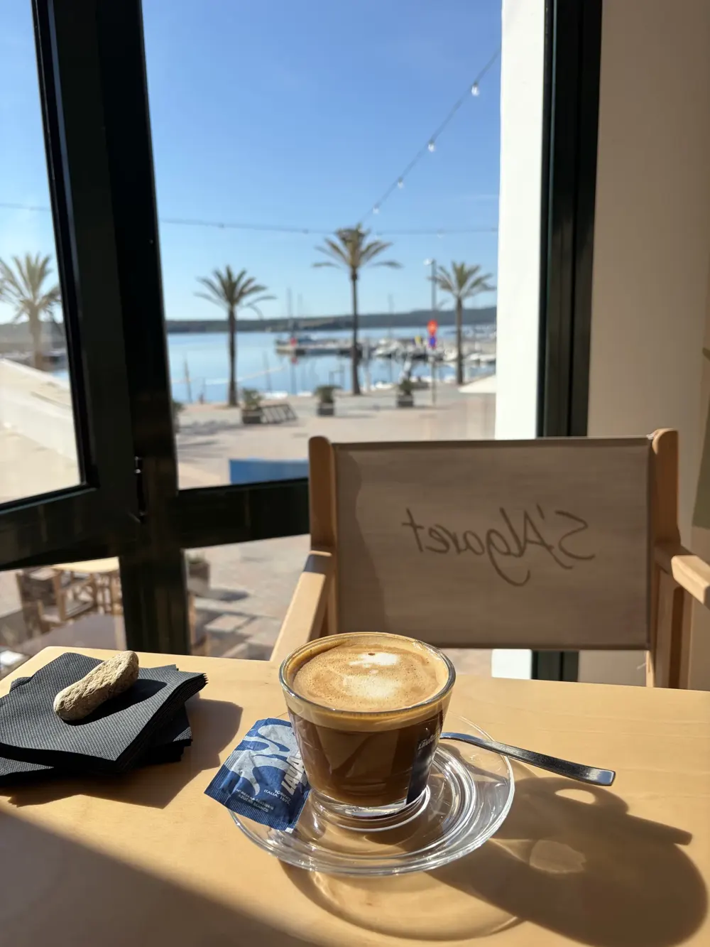 Café en una mesa junto a la ventana del Hotel S'Algaret